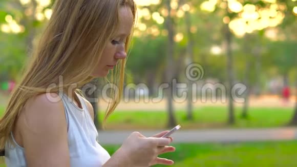 Steadycam拍摄的一个年轻女子坐在一个使用手机的公园里视频的预览图