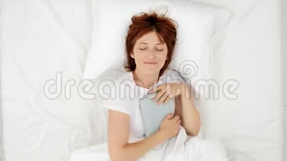 女人躺在床上手上拿着书睡着了顶部视图视频的预览图