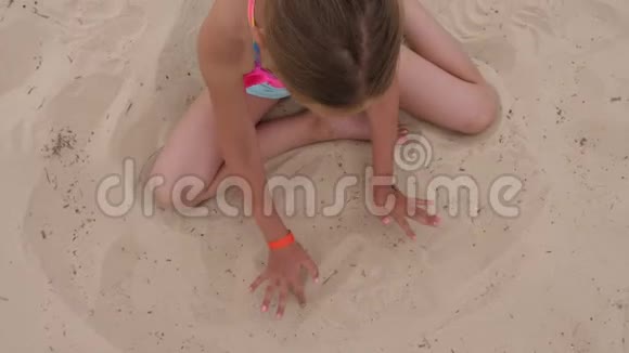 可爱的金发女孩在沙滩上找到蓝色凉鞋视频的预览图