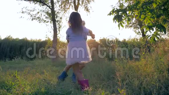 乡村假日小男孩和小女孩一起在夕阳下手牵着手缓慢地盘旋视频的预览图