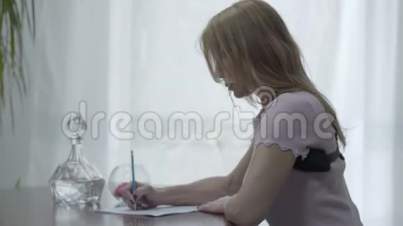 肖像美丽的苗条的金发的女人穿着骨科胸衣坐在桌子上写着一封信视频的预览图