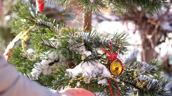 特写镜头一位女士用圣诞装饰装饰圣诞树圣诞玩具挂在白雪覆盖的地上视频的预览图