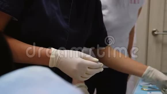 戴橡胶白手套的牙医用钳子拿一个工具来拧紧系统的支架或拆下牙齿视频的预览图