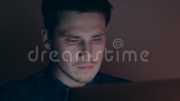 一个晚上在电脑上工作的男性的肖像男人在黑暗的房间里浏览互联网视频的预览图
