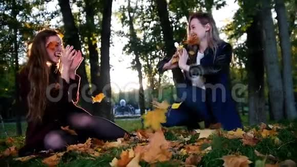 秋天公园里快乐的女孩互相扔橙色的叶子慢动作视频的预览图