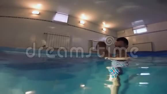 一家人正在游泳池里游泳父亲在教他的儿子这个小儿子成功地应付了这一企图视频的预览图