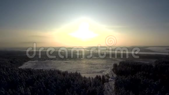 降雪时日落的鸟瞰图村近田和冬林雪中农舍的树木道路和屋顶视频的预览图