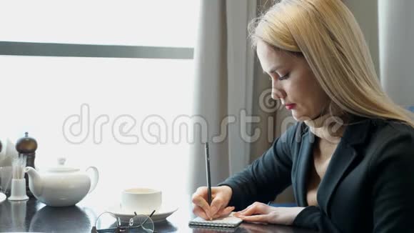 小女孩在做作业在坐在咖啡馆的记事本上写笔记视频的预览图