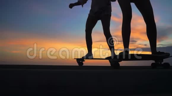 两个穿着短裤和运动鞋的女朋友在山坡上踩着美丽的滑板腿上的特写视频的预览图