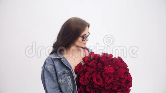 一位留着长发的女士嗅着一束红玫瑰视频的预览图