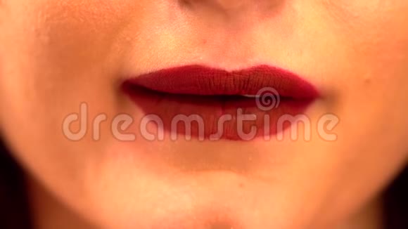 年轻的女性舔着嘴唇近镜头的美丽女人舌头舔她的嘴唇与明亮的深红色李子浆果视频的预览图