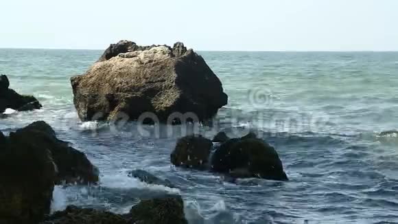 海浪拍打着海岸岩石和树荫下的岩石视频的预览图