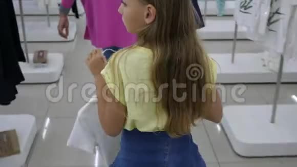 一个金发女孩带着衣服去时装室视频的预览图