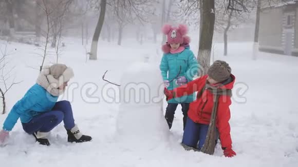 妈妈和两个女儿一起塑造了雪人户外冬季家庭游戏视频的预览图