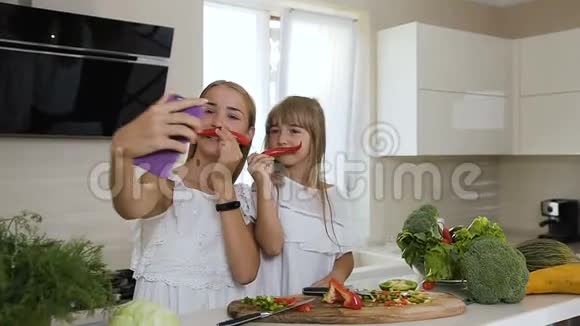 两个穿着白色衣服的长发姐妹展示了红辣椒的胡子并制作了自拍照片视频的预览图