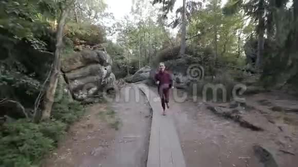 快乐的女人在石头和石头之间穿过一个旅游通道稳定相机跟踪镜头视频的预览图