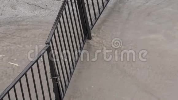 城市洪水中的洪水街道水流过一扇锁着的大门视频的预览图