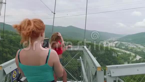 两个红头发的年轻女子和金发女子在上面的青山山谷里互相拍照视频的预览图