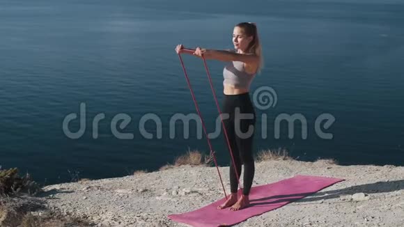 女人在户外用橡皮筋锻炼身体锻炼身体慢动作视频的预览图