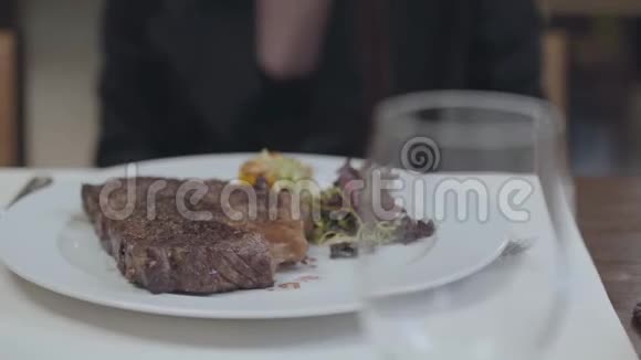美味的牛排蔬菜和叶子躺在盘子里在餐厅的女人面前酒精饮料视频的预览图