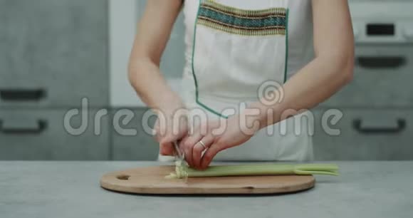 厨房衣柜里的女人用一把大刀切了一根大芹菜用专业刀切视频的预览图