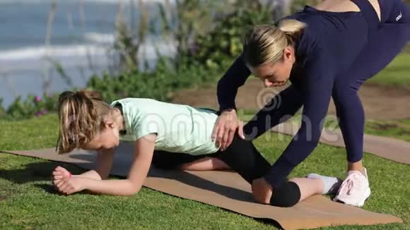 一群年轻女性白天在海边练习瑜伽绿草体操教练培训员视频的预览图