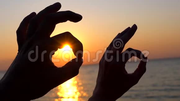 女人和男人的手显示标志可以快乐的一对情侣在海边沙滩水户外背景下展示象征OK视频的预览图