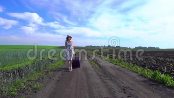 开朗的女孩带着手提箱在路上行走视频的预览图