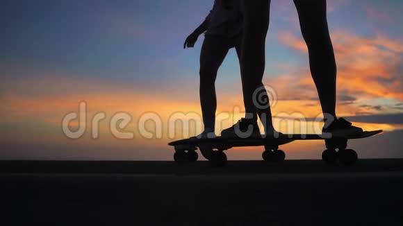 两个穿着短裤和运动鞋的女朋友在山坡上踩着美丽的滑板腿上的特写视频的预览图
