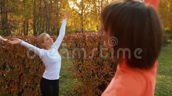 健身女性在秋季公园的户外课堂上训练瑜伽锻炼城市公园练习瑜伽体式的女性团体视频的预览图