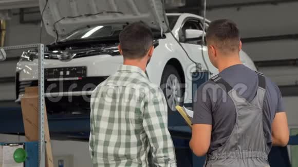 一名机械师和顾客在车库握手的后景镜头视频的预览图