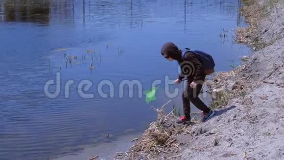 男孩正在用蝴蝶网在河上宣泄青蛙的户外自然探索视频的预览图