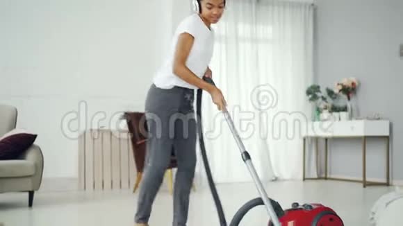 美丽的年轻女士正在打扫房子的地板听音乐享受旋律和舞蹈现代视频的预览图