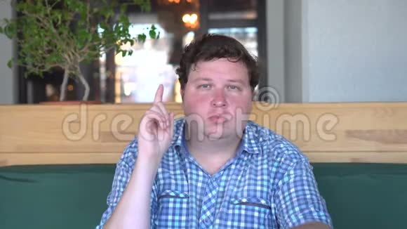 一个年轻的胖子在咖啡馆或餐馆里有想法和手指的画像视频的预览图