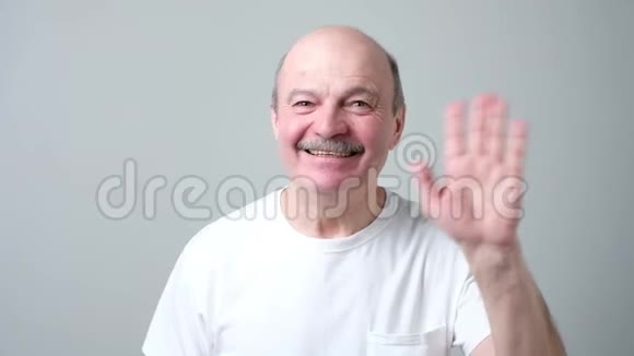 欧洲的退休老人一边高兴地微笑着一边打招呼一边挥手视频的预览图