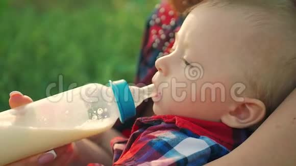 妈妈在户外用一瓶牛奶喂她的小儿子视频的预览图