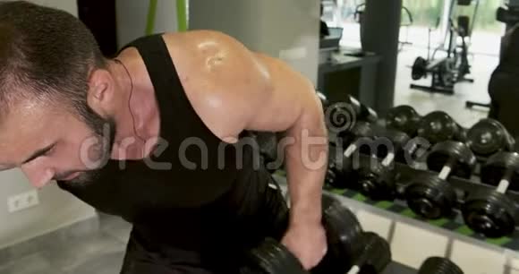 年轻强壮的男子进行倾斜哑铃按压健身房锻炼剧烈运动举重健美视频的预览图