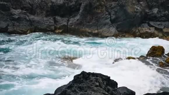 多云天气下岩石海岸附近强烈的海浪特写视频的预览图