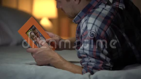 绝望的年轻人躺在床上和女朋友看着照片悲伤视频的预览图