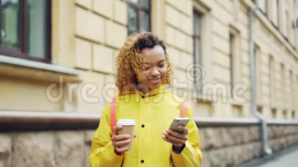 迷人的混血女人正在使用现代智能手机看屏幕微笑着上网或看照片视频的预览图