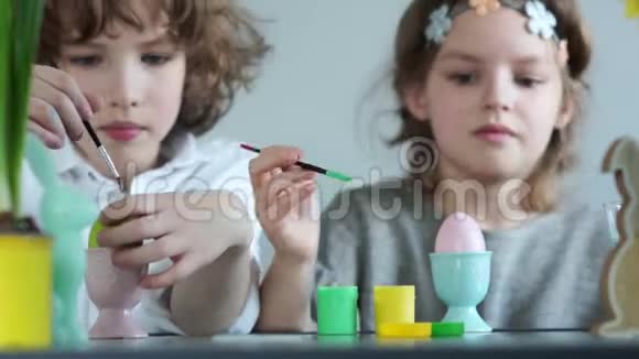 兄妹在复活节装饰的背景上画鸡蛋孩子们一个小男孩和一个女孩正在准备视频的预览图