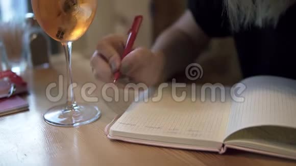 长发金发的女人坐在一家现代化的咖啡馆里在她的笔记本上做了一些笔记一杯酒视频的预览图
