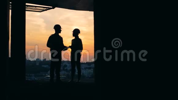建筑师站在未完工的建筑日落背景视频的预览图