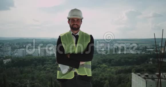 建筑师或建筑商站在建筑的顶部安全帽对着镜头微笑视频的预览图