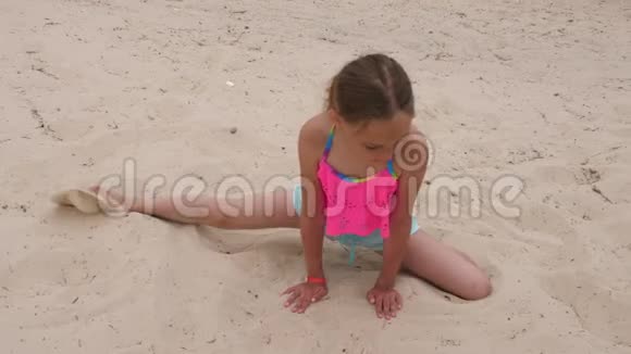 年轻的运动女孩在沙滩上做右半裂伸展运动视频的预览图