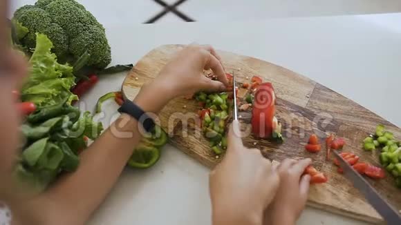 青少年女孩用菜刀近距离射击手学习切青椒蔬菜准备食物视频的预览图