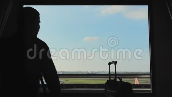一个年轻人从旅馆房间的窗户看飞机起飞视频的预览图