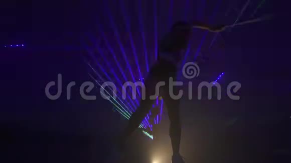 在激光表演中穿着紧身衣服和运动鞋的漂亮体操运动员带着丝带跳舞动作缓慢视频的预览图