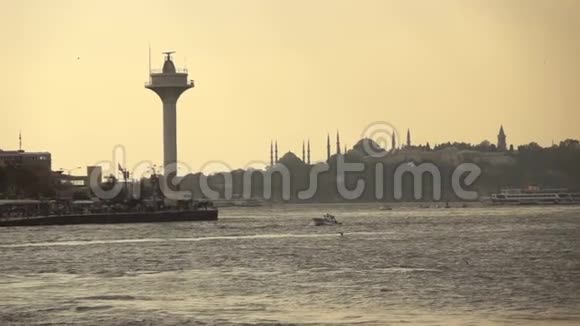 拥有土耳其伊斯坦布尔古老历史建筑的海景日落时拥有古老的清真寺和海上灯塔视频的预览图