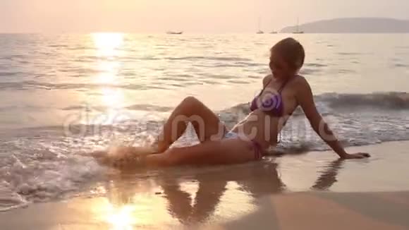 坐在夕阳下的海浪中的女人视频的预览图